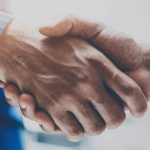Close up view of business partnership handshake.Concept two businessman handshaking process.Successful deal after great meeting.Horizontal, flare effect, blurred background